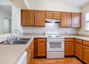 Thumbnail 2 of 14 - A kitchen with wooden cabinets and a white stove top oven Fishermans Landing Apartments in Ormond Beach, FL