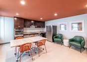 Thumbnail 4 of 14 - a dining room with a table and chairs and a kitchen with a refrigerator at 140 Clarendon, Boston MA.