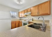 Thumbnail 10 of 17 - Kitchen Layout With Modern Appliances, Light Countertops, and Wooden Cabinetry at Creekwood Apartments, Watertown, NY.