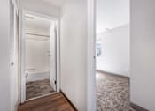 Thumbnail 19 of 21 - A white hallway with a bathroom visible through the door.