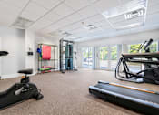 Thumbnail 13 of 21 - A gym with a treadmill, exercise bike, and other equipment.