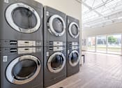 Thumbnail 15 of 21 - A row of front-loading washing machines in a laundromat.