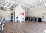 Thumbnail 16 of 21 - A laundromat with a row of washers and dryers.