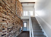 Thumbnail 12 of 21 - A staircase with a brick wall on one side and a white wall on the other.