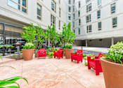 Thumbnail 8 of 14 - A courtyard with red chairs and plants at Pok Oi Residences, Boston, MA, Massachusetts, 2111