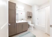 Thumbnail 12 of 12 - A bathroom with brown cabinets and a white toilet. at The Anne M. Lynch Homes at Old Colony, South Boston, Massachusetts