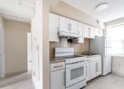 Thumbnail 3 of 17 - A kitchen with white appliances and cabinets.