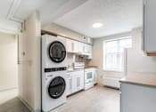 Thumbnail 2 of 17 - A white kitchen with a washer and dryer built in.