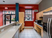 Thumbnail 8 of 15 - A kitchen with a red wall and a stainless steel refrigerator at The Cordovan at Haverhill Station, Haverhill, MA
