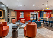 Thumbnail 9 of 15 - A room with orange chairs and a television on the wall at The Cordovan at Haverhill Station, Haverhill, MA