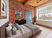 Thumbnail 2 of 15 - A bedroom with a bed, a dresser, and a window at The Cordovan at Haverhill Station, Haverhill, MA