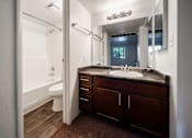 Thumbnail 34 of 42 - A bathroom with a brown counter top and a white toilet.