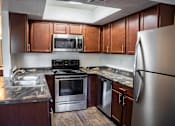 Thumbnail 33 of 42 - A kitchen with a stainless steel refrigerator, microwave, oven, and sink.