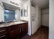 Thumbnail 36 of 42 - A bathroom with a sink, mirror, and a washer and dryer.
