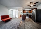 Thumbnail 38 of 42 - A red couch sits in a spacious kitchen and living room with wood flooring and modern appliances.