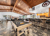 Thumbnail 2 of 18 - A billiard table is in the middle of a room with a bar and stools.