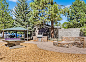 Thumbnail 3 of 18 - A backyard with a picnic table, a fire pit, and a stone wall.