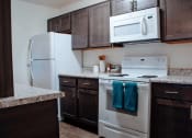 Thumbnail 16 of 26 - a kitchen with white appliances and dark wood cabinets