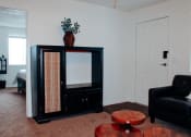 Thumbnail 21 of 26 - a living room with a black chair and a black china cabinet with a plant on top