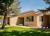 Thumbnail 21 of 34 - A house with a brown siding and a tan roof with a small garden in front.
