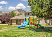 Thumbnail 34 of 34 - A playground with a blue slide and a red slide in front of a house.