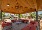 Thumbnail 11 of 34 - A patio with a table and chairs under a wooden roof.