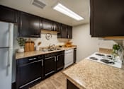 Thumbnail 2 of 34 - A kitchen with black cabinets and a granite countertop.