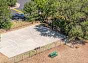 Thumbnail 14 of 32 - A basketball court surrounded by trees and a fence.