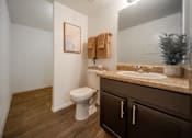 Thumbnail 24 of 32 - A bathroom with a toilet, sink, and wooden floors.