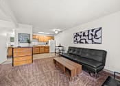 Thumbnail 9 of 20 - A living room with a black leather couch and a wooden coffee table.