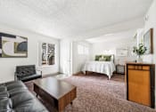 Thumbnail 16 of 20 - A living room with a black leather couch and a wooden coffee table.