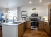 Thumbnail 31 of 32 - a kitchen with white cabinets and a large white island with a stainless steel sink and oven