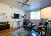 Thumbnail 18 of 32 - a living room with a ceiling fan and a tv on the wall