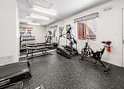 Thumbnail 4 of 16 - A fitness center with a treadmill, stationary bike, and weights.