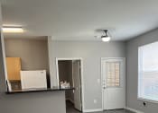 Thumbnail 4 of 17 - an empty living room with a kitchen and a white door
