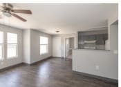 Thumbnail 9 of 10 - an empty living room with a ceiling fan and a kitchen