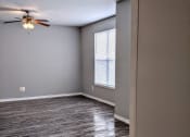 Thumbnail 7 of 17 - an empty living room with a ceiling fan and a window