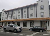 Thumbnail 3 of 9 - a building with a brown and white facade and a black car parked in front of it
