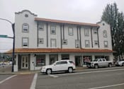 Thumbnail 2 of 9 - a building on the corner of a street with cars parked in front of it