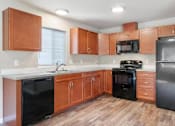 Thumbnail 8 of 48 - A kitchen with wooden cabinets and black appliances.