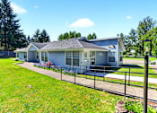 Thumbnail 1 of 17 - A house with a grey roof and a fence in front of it.