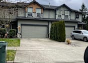 Thumbnail 1 of 82 - A grey house with a grey car parked in front.
