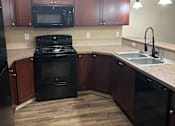 Thumbnail 49 of 82 - A kitchen with wooden cabinets and black appliances.