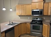 Thumbnail 30 of 82 - A kitchen with wooden cabinets and black appliances.