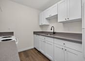 Thumbnail 26 of 42 - A kitchen with white cabinets and a grey countertop.