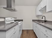 Thumbnail 27 of 42 - A kitchen with white cabinets and a stove top oven.