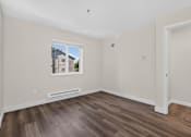 Thumbnail 40 of 42 - A bedroom with wood plank flooring and a window with heating at Ridgeline Apartments