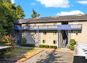 Thumbnail 3 of 42 - A large apartment building with a red driveway in front.