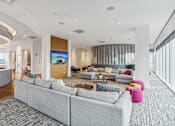 Thumbnail 17 of 26 - A modern living room with a grey sofa and a large screen on the wall.