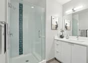 Thumbnail 5 of 26 - A white bathroom with a glass shower and a white vanity.